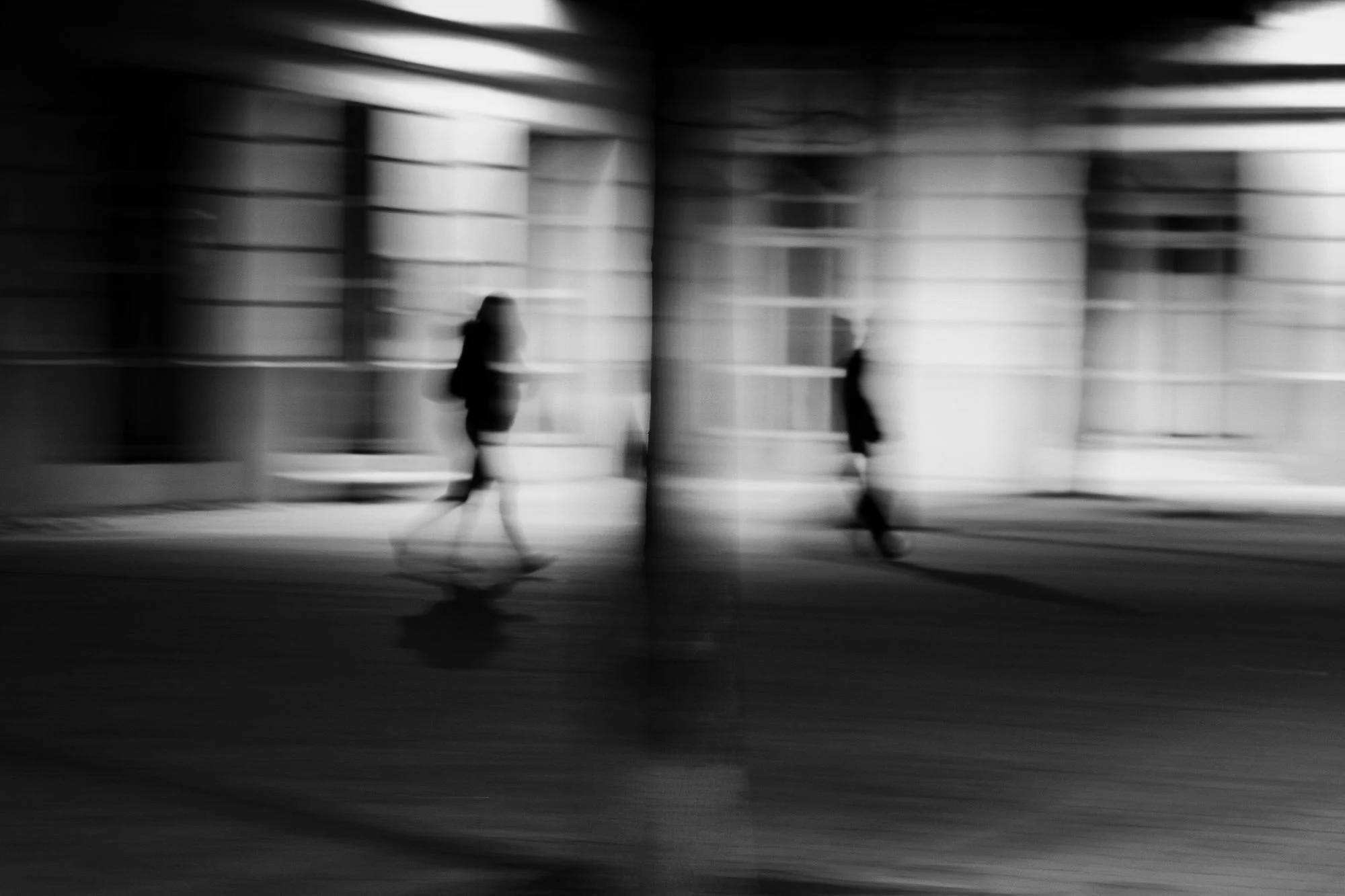 Silhouettes floues de passants dans une rue, photographie en noir et blanc