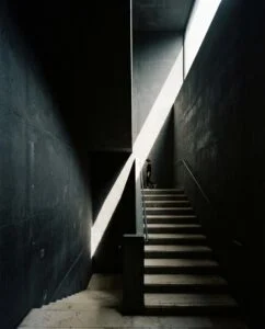 Escalier sombre traversé par un rayon de lumière, photographie de Milo Chen
